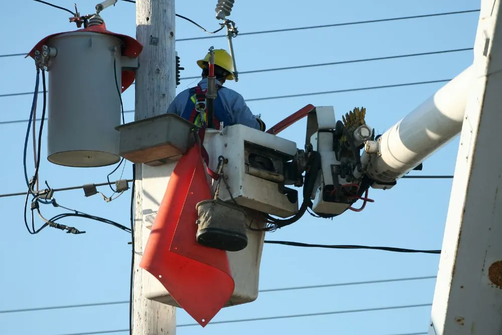 Stock photo: a lineman in a bucket truck working on a transformer at the top of a power pole.